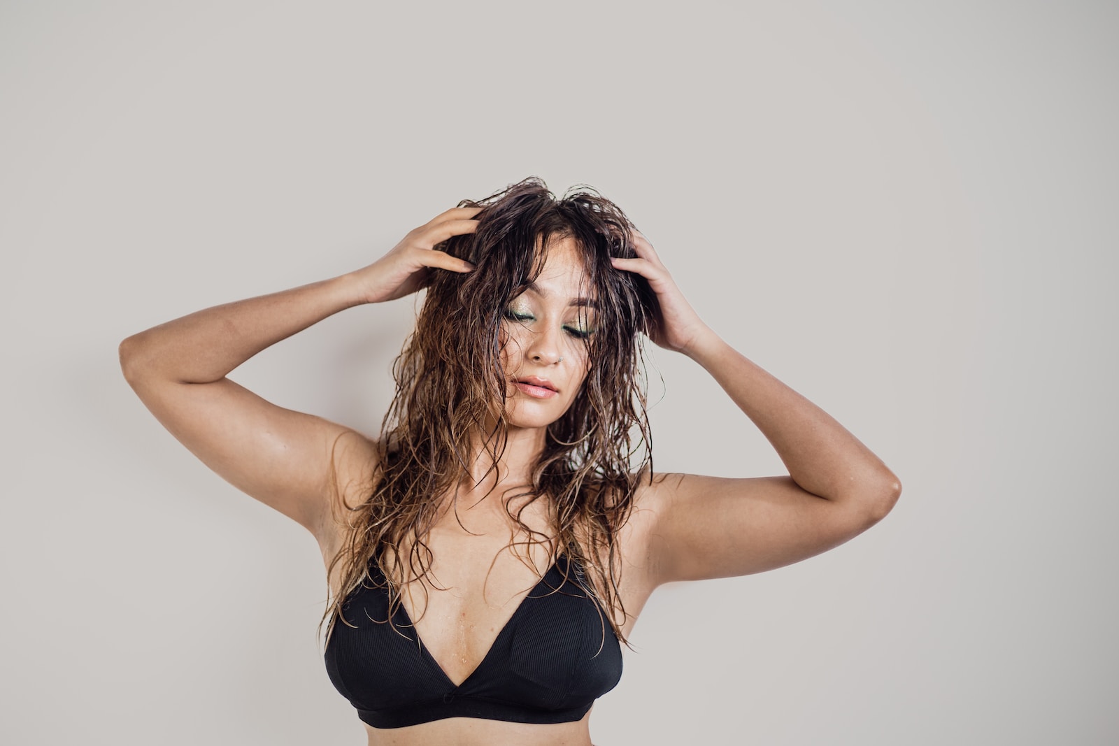 a woman in a black bikini top holding her hair